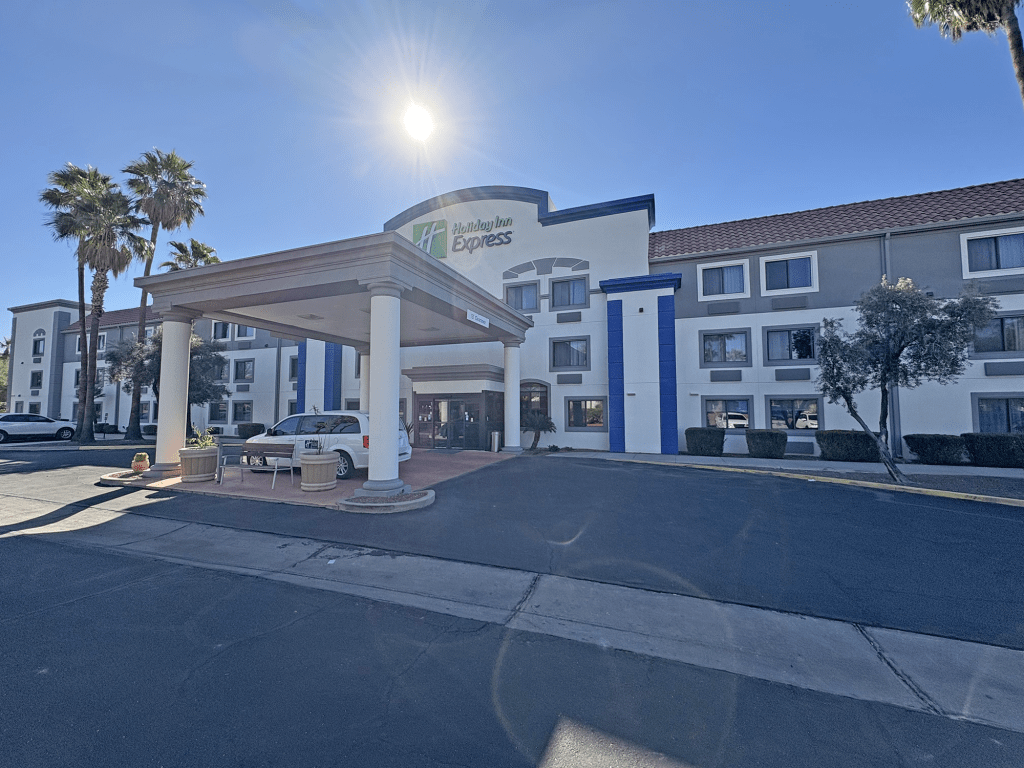 Exterior view of Holiday Inn Express Tucson Airport, showcasing the main entrance with palm trees and blue sky.