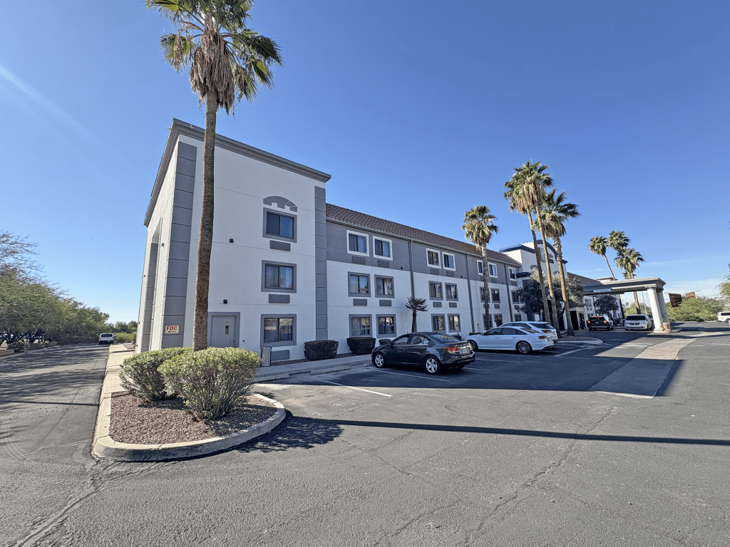 Exterior view of the Holiday Inn Express Tucson Airport, showcasing the building's modern architecture and landscaping under a clear blue sky.