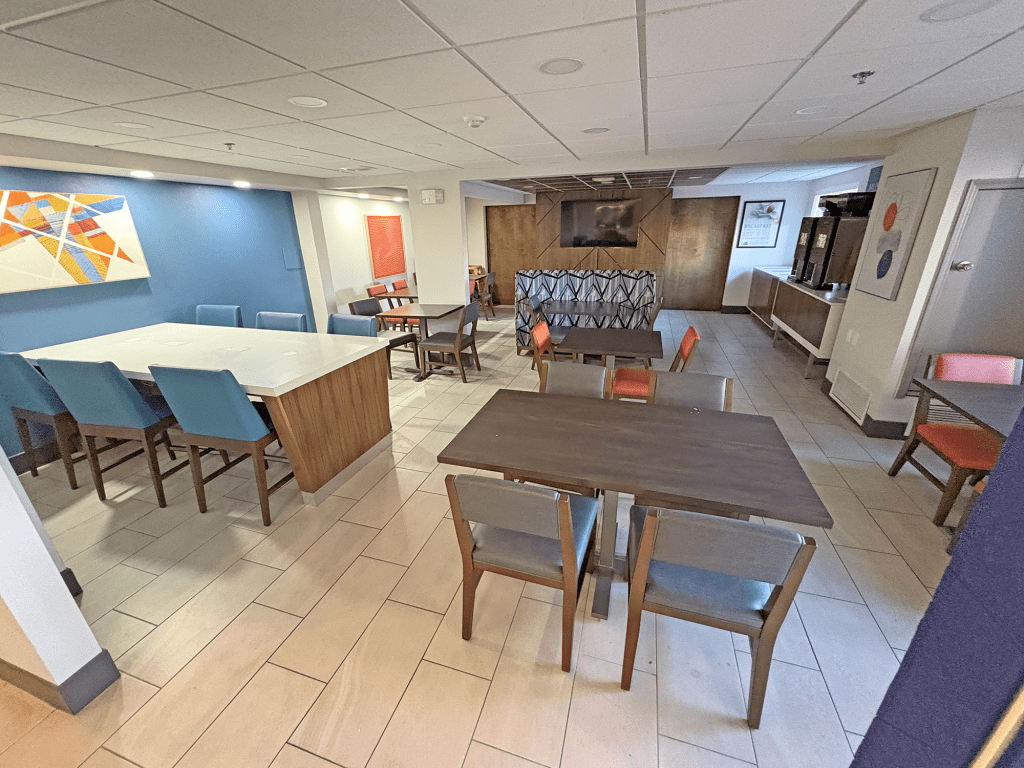 Interior view of the dining area and business center at Holiday Inn Express Tucson Airport, featuring modern furnishings and a bright color scheme.